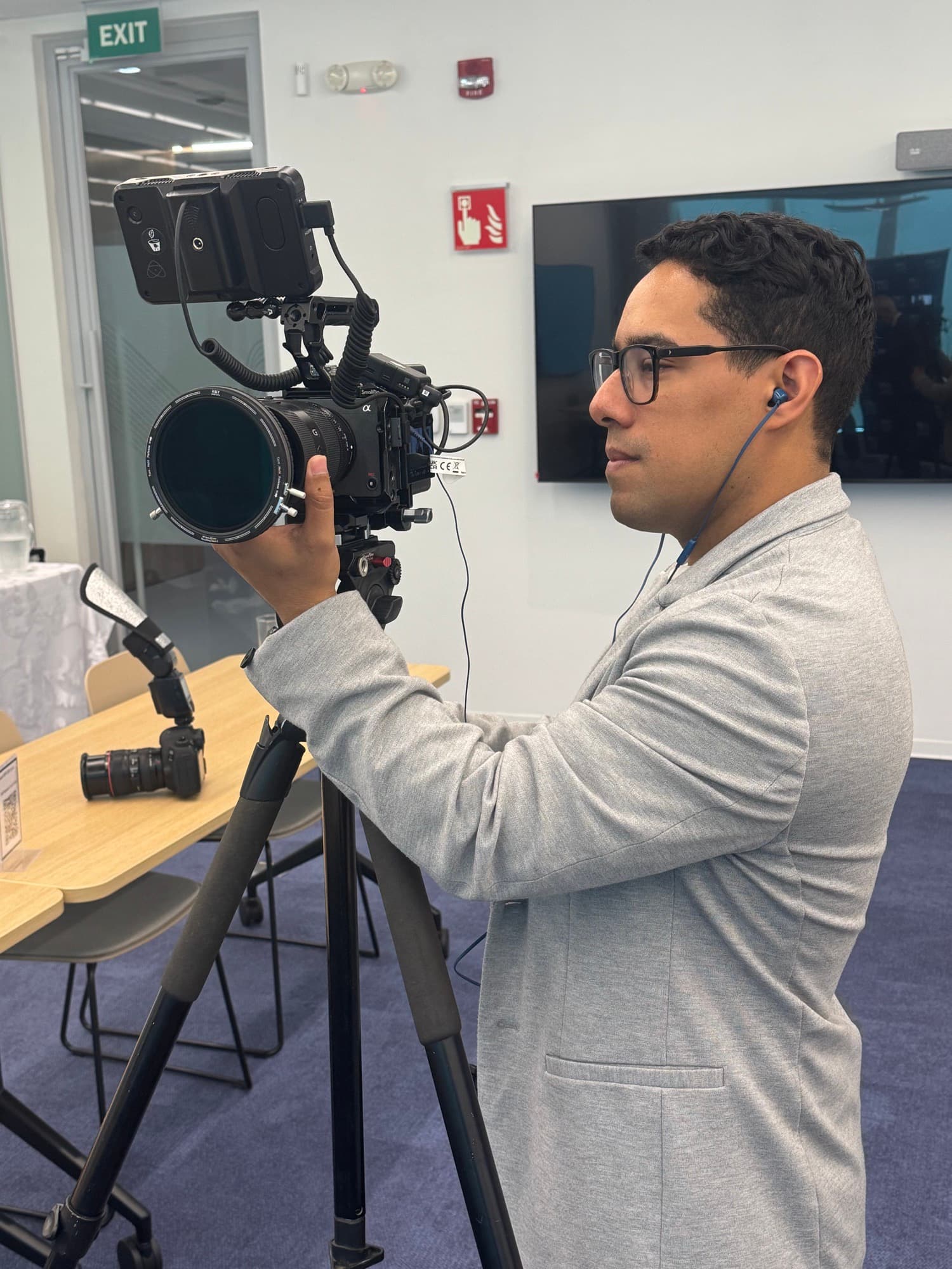 Andrés López operando una cámara de cine en trípode durante un rodaje corporativo en interiores